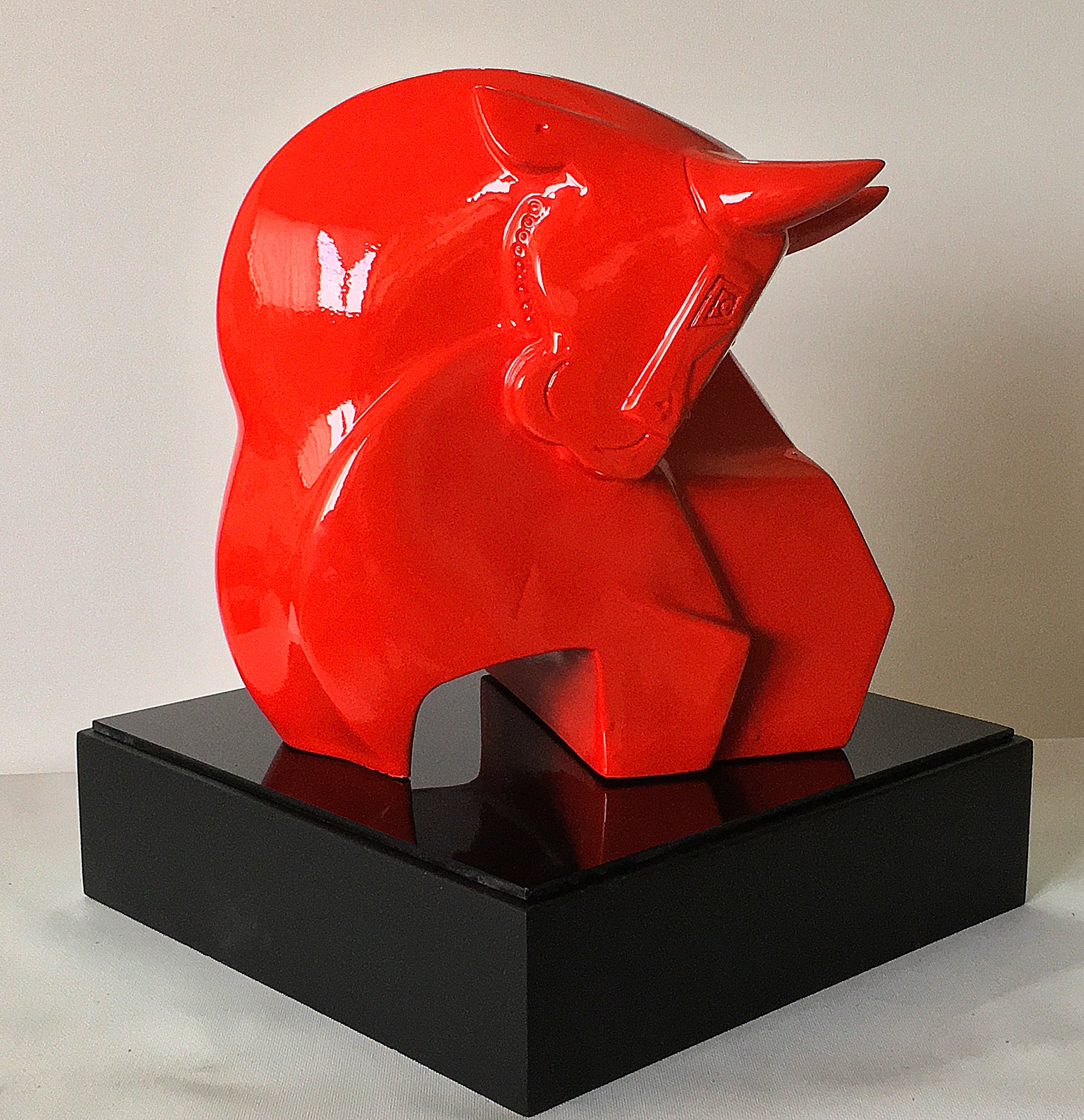 A high-gloss red fiberglass sculpture of a stylized bull titled 'Orthodox' by Dinkar Jadhav, mounted on a square black base.