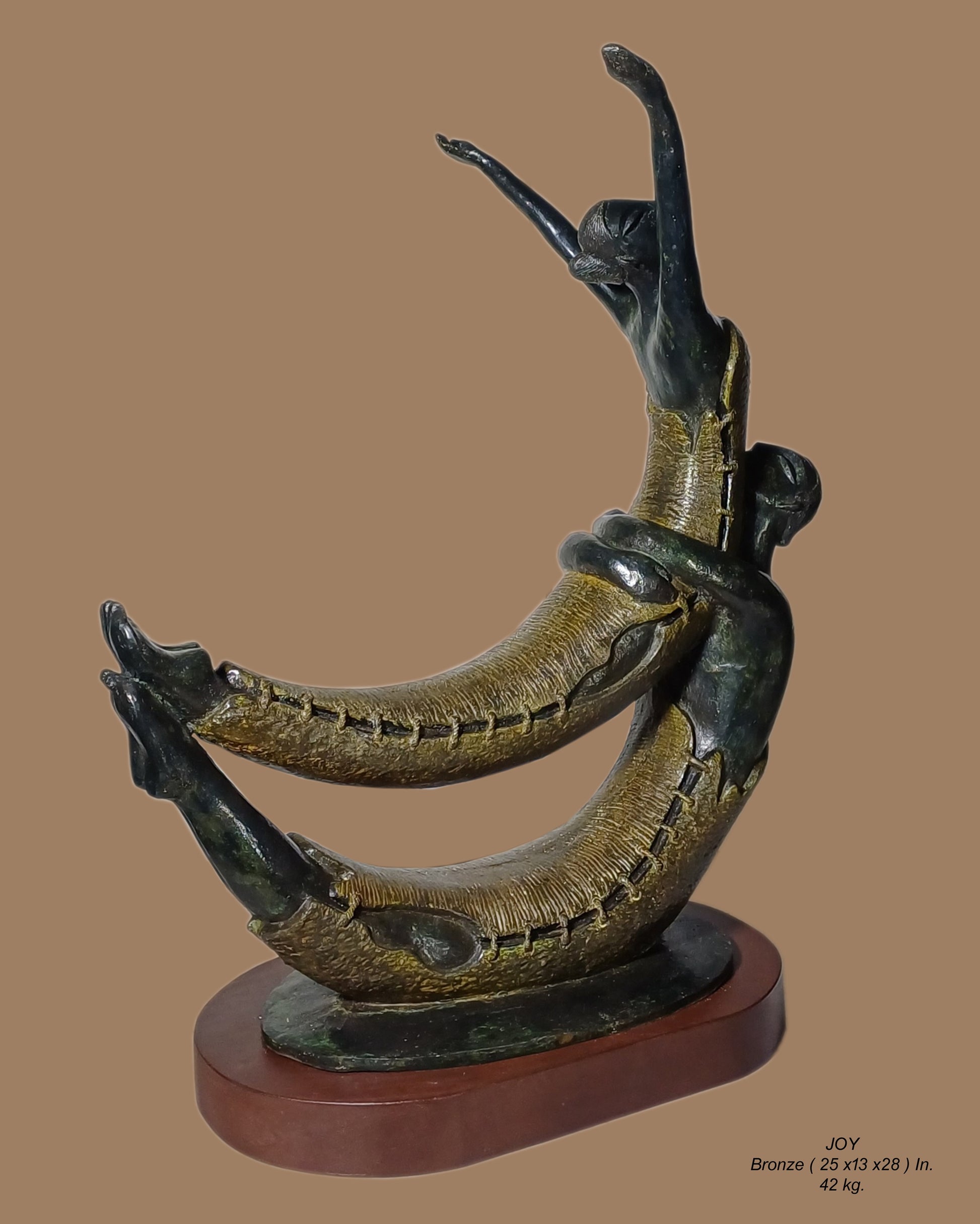Subrata Paul contemporary Indian bronze sculpture titled Joy featuring two intertwined figures in a dynamic crescent arc with gold patinated stitched texture on a wooden base